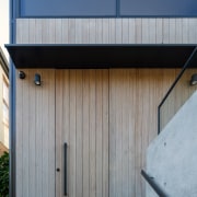 An understated front door disappears into the cladding. 