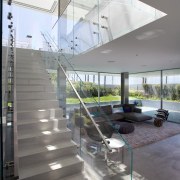 The first floor of this beachhouse accommodates a apartment, architecture, condominium, daylighting, glass, handrail, house, interior design, mixed use, real estate, stairs, structure, gray, white