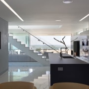 Backpainted glass cabinets in this galley-style kitchen reflect architecture, ceiling, daylighting, glass, handrail, house, interior design, kitchen, gray