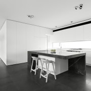Positioned between the two living areas, the kitchen architecture, black and white, countertop, floor, house, interior design, kitchen, real estate, white, black