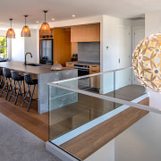 A David Trubridge light hangs in prominence adjacent architecture, building, cabinetry, ceiling, countertop, design, dining room, floor, flooring, furniture, hall, home, house, interior design, kitchen, material property, property, real estate, room, shelf, table, tile, wall, gray