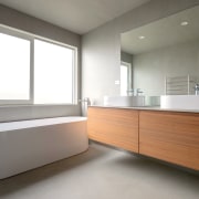 A clean-lined wall-hung vanity contrasts a curvaceous freestanding architecture, bathroom, building, cabinetry, ceiling, daylighting, floor, flooring, furniture, home, house, interior design, material property, property, real estate, room, sink, gray, white