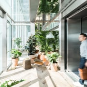 The elevator trough which visitors enter the building architecture, balcony, building, daylighting, door, facade, flowerpot, glass, home, house, houseplant, interior design, plant, property, real estate, room, window, white