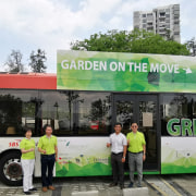 The Singapore green-roofed 10-bus initiative  is called "Gardens advertising, architecture, bus, car, commercial vehicle, mode of transport, motor vehicle, tour bus service, tourism, transport, tree, vehicle, gray, black, white