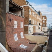 Alex Chinneck – From the knees of my apartment, architecture, blue, brick, brickwork, building, facade, home, house, neighbourhood, property, real estate, residential area, roof, street, town, urban area, wall, window, gray
