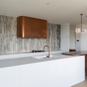 The veined, marble-look splashback accentuates the copper rangehood 