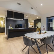 The kitchen features soft black matt cabinetry, brass 