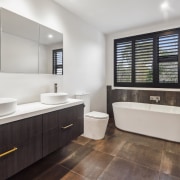 Master ensuite with dark-wood vanity and rich-toned tile 