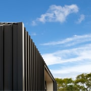 The first floor addition is a metal clad architecture, blue, building, cloud, commercial building, corporate headquarters, daytime, facade, house, line, real estate, sky, teal, black