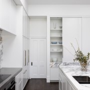 The kitchen features white cabinetry, dark floors and 