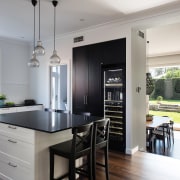 ​​​​​​​In this heart-of-the-home kitchen, the tall black pantry countertop, classique, interior design, kitchen, cabinetry, black, white, Caesarstone, wine fridge, vintec, IL Design, 