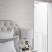 The layered and textured bedroom features a grass-cloth 