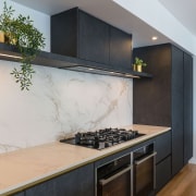 Black cabinetry plays against stone-look splashback and perimeter 
