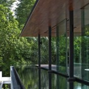 Ripples on the water enliven the interior spaces. architecture, building, cottage, home, house, pavilion, porch, property, real estate, room, shade, tree, window, black, green