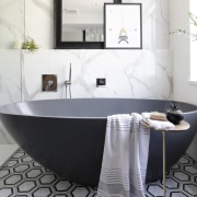 A honed bluestone freestanding tub adds a modern 