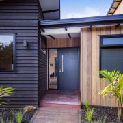 The front of this Waitoki home - Entrance architecture, backyard, cottage, door, facade, home, house, property, real estate, residential area, siding, window, gray
