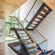 The feature staircase connects all levels of the architecture, daylighting, glass, handrail, house, interior design, product design, stairs, structure, wood, gray, orange