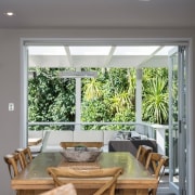 The dining area opens to forest views and ceiling, home, house, interior design, living room, table, window, gray