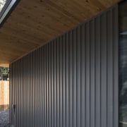 A wood-lined soffit runs along the outside of architecture, daylighting, facade, house, real estate, roof, shed, siding, wall, window, wood, black, gray