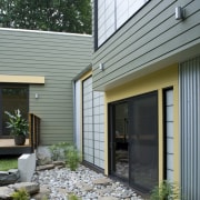 A rock garden sits outside this hallway - backyard, cottage, courtyard, facade, home, house, real estate, residential area, siding, window, yard, gray