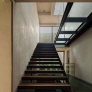 A glass walkway runs above the staircase - architecture, daylighting, handrail, house, interior design, stairs, black, brown, gray