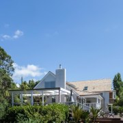 A side view of the house with variety architecture, cottage, estate, facade, farmhouse, home, house, property, real estate, residential area, roof, sky, suburb, tree, teal