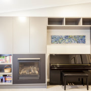 A piano, fireplace and bookshelf sit alongside one furniture, interior design, room, shelving, white