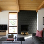 The fireplace is surrounded with black brick - architecture, ceiling, daylighting, fireplace, floor, hardwood, hearth, home, house, interior design, living room, real estate, room, wall, window, wood, wood flooring, black