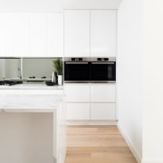 Furthering a theme of symmetry found throughout parts angle, countertop, floor, flooring, interior design, kitchen, laminate flooring, product, product design, wood flooring, white