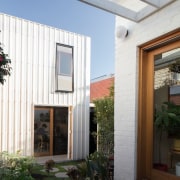 Pavers link the two buildings in this courtyard architecture, courtyard, daylighting, facade, home, house, property, real estate, residential area, siding, window, white