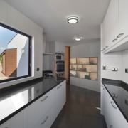 The narrow galley-style kitchen features translucent cupboards architecture, countertop, daylighting, interior design, kitchen, property, real estate, gray