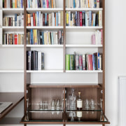 A drinks cabinet sits beneath this bookshelf in bookcase, furniture, library, public library, shelf, shelving, white