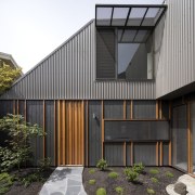 The wood door stands in contrast to the architecture, building, courtyard, facade, home, house, real estate, residential area, siding, black, gray