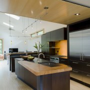 Wood runs above the kitchen, breaking up the architecture, cabinetry, ceiling, countertop, floor, hardwood, interior design, kitchen, wood flooring, gray