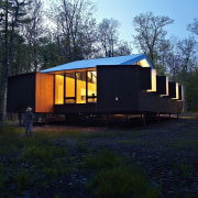 At night, the elevated cabin lights up - architecture, cottage, home, house, hut, log cabin, real estate, shack, shed, tree, black