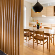 This large lamp dominates the kitchen, acting as dining room, floor, flooring, furniture, hardwood, interior design, laminate flooring, light fixture, room, table, wall, wood, wood flooring, brown, orange, white