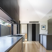 The island conceals the dishwasher and sink, while architecture, cabinetry, ceiling, countertop, daylighting, floor, hardwood, house, interior design, kitchen, laminate flooring, real estate, wood flooring, white