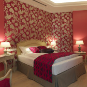 Wood floors and recessed lighting compliment the floral bed, bed frame, bed sheet, bedroom, ceiling, home, hotel, interior design, room, suite, textile, wall, wallpaper, red, brown