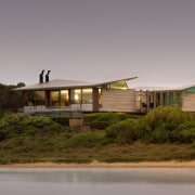 From the water, the home appears to rise architecture, cottage, home, house, landscape, property, real estate, roof, sky, gray, brown