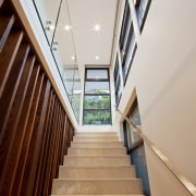 In this home by designer James Cooper, the apartment, architecture, ceiling, daylighting, estate, floor, handrail, house, interior design, lobby, property, real estate, stairs, window, wood, gray