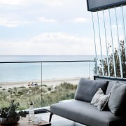 A glass balustrade keeps sea in full view chair, couch, furniture, home, interior design, living room, outdoor furniture, sea, sky, sunlounger, table, window, white