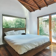In the bedroom, plentiful use of glass and architecture, bed, bed frame, bedroom, ceiling, daylighting, estate, floor, hardwood, home, house, interior design, mattress, real estate, room, window, wood, wood flooring, gray, brown
