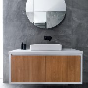 A cantilevered, clean-lined vanity cabinet and accompanying round architecture, bathroom, bathroom accessory, bathroom cabinet, ceramic, chest of drawers, floor, flooring, furniture, interior design, material property, mirror, room, sink, tap, tile, wall, wood, gray