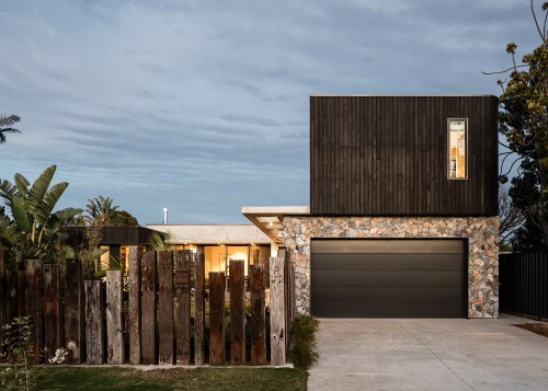 A garage, flanked in natural stone and black 