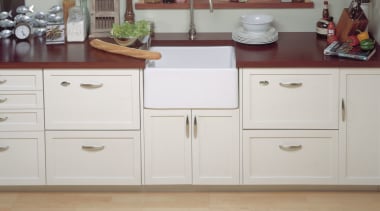 Kitchen with concealed appliances. Sink and faucetry between cabinetry, chest of drawers, countertop, cuisine classique, cupboard, drawer, filing cabinet, floor, furniture, hardwood, home appliance, kitchen, room, sideboard, wood stain, gray