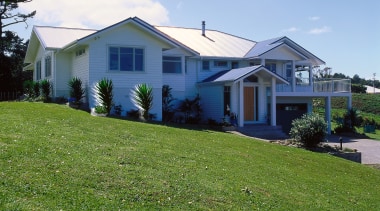 A photograph of a house built on a architecture, backyard, cottage, estate, facade, farmhouse, grass, home, house, land lot, landscape, lawn, neighbourhood, plant, plantation, property, real estate, residential area, rural area, siding, sky, suburb, tree, yard, green