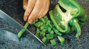 Closeup of granite benchtop with someone chopping vegetables. green, local food, vegetable, black, green