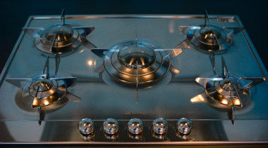 Closeup of five-burner gas hob with stainless steel black, teal