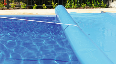 Swimming pool with blue cover being rolled up. azure, blue, leisure, swimming pool, water, teal, blue