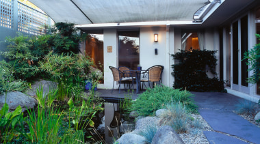 View of the patio area, concrete slab blocks backyard, cottage, courtyard, garden, home, house, landscaping, outdoor structure, patio, plant, property, real estate, roof, yard, white